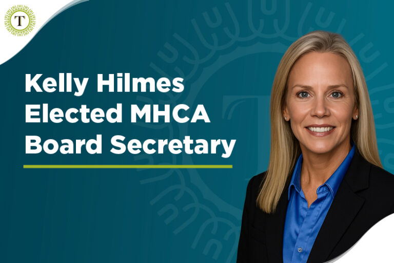Professional headshot of a smiling woman in a blue shirt and blazer, next to text reading “Kelly Hilmes Elected MHCA Board Secretary” on a teal background with a circular logo in the corner, celebrating the recent achievement as Kelly Hilmes is elected to this prestigious position.