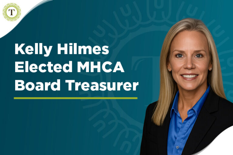 Professional woman in a blue shirt and blazer smiles beside the text “Kelly Hilmes Elected MHCA Board Treasurer” on a blue background, highlighting the recent announcement of Kelly Hilmes elected to this esteemed position; a circular logo appears in the top left corner.