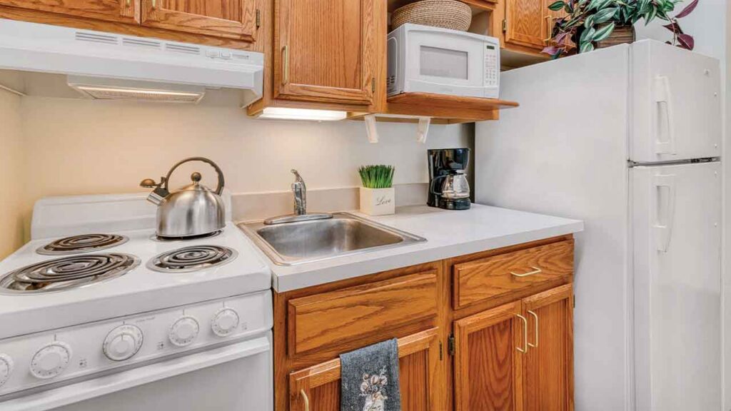 Kitchen area with oak cabinets, white appliances including a stove, microwave, and refrigerator, and a stainless steel sink.